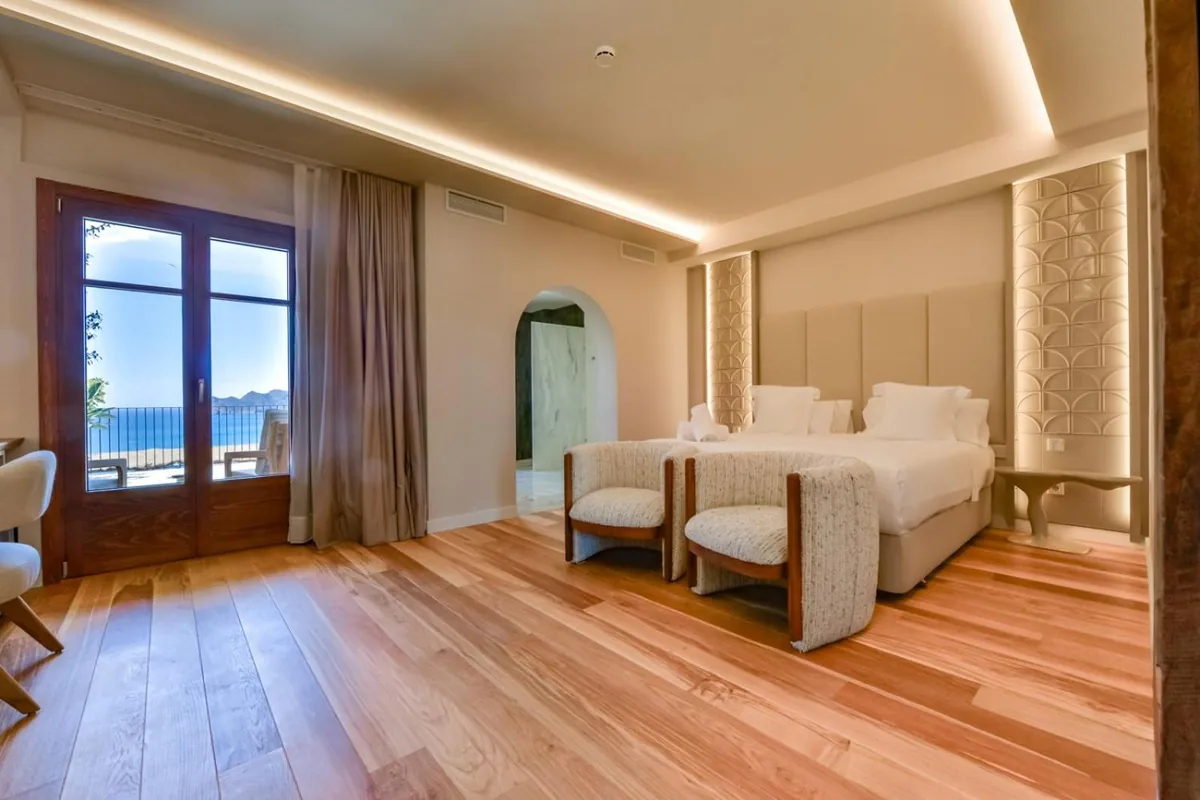 Suite bedroom with a sea-view door and arched bathroom entrance at Las Torres
