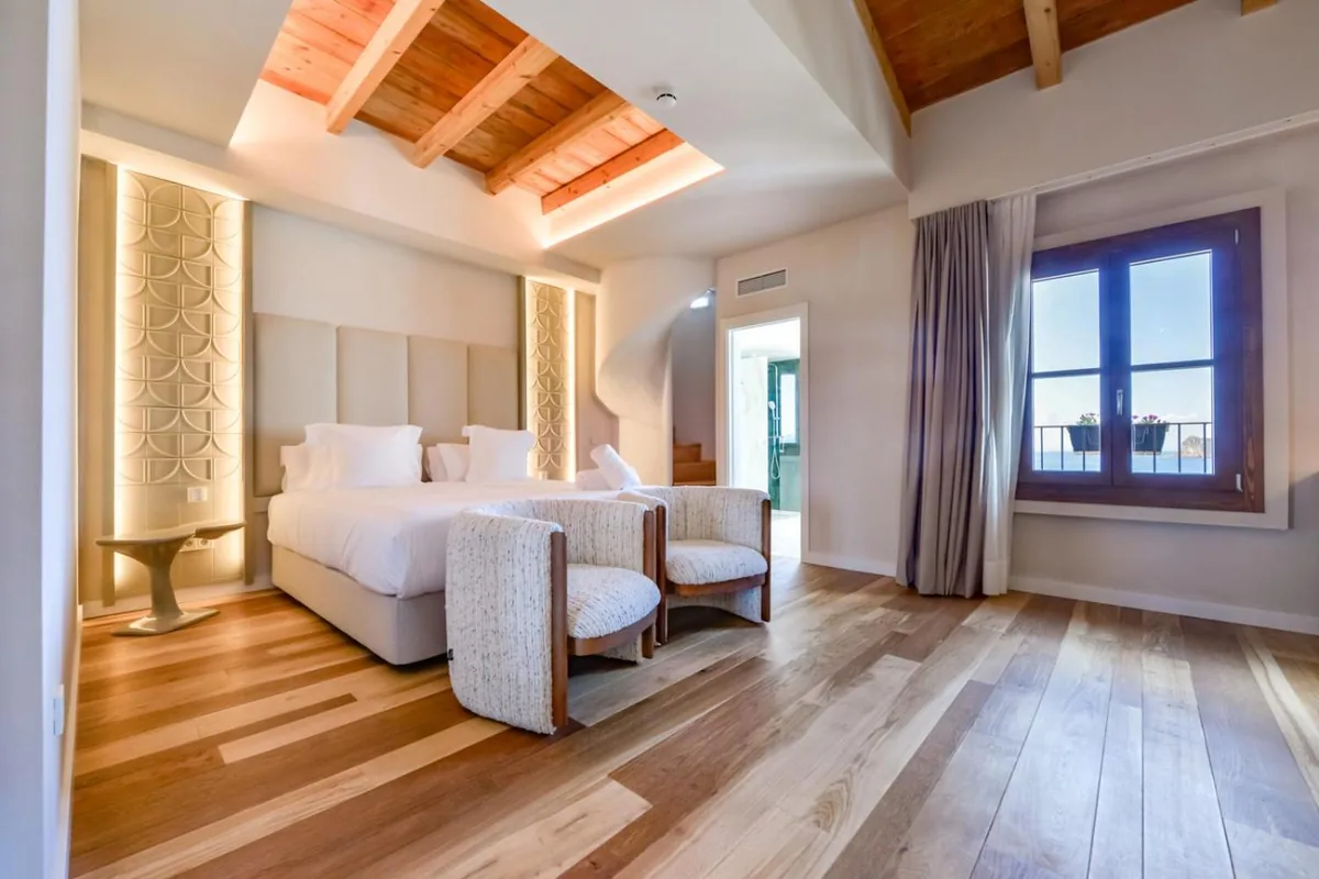 Suite bedroom with a timber ceiling and sea-view window at Las Torres
