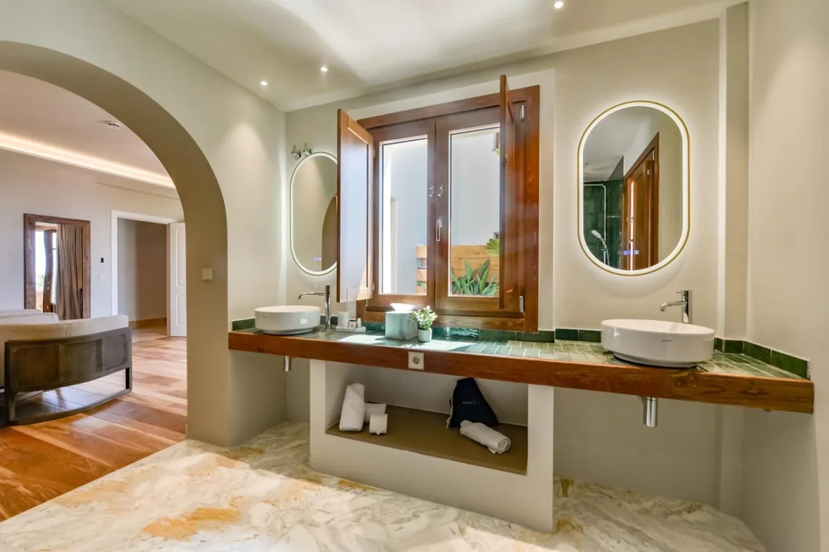 Suite bathroom with double washbasins and an arched doorway at Las Torres