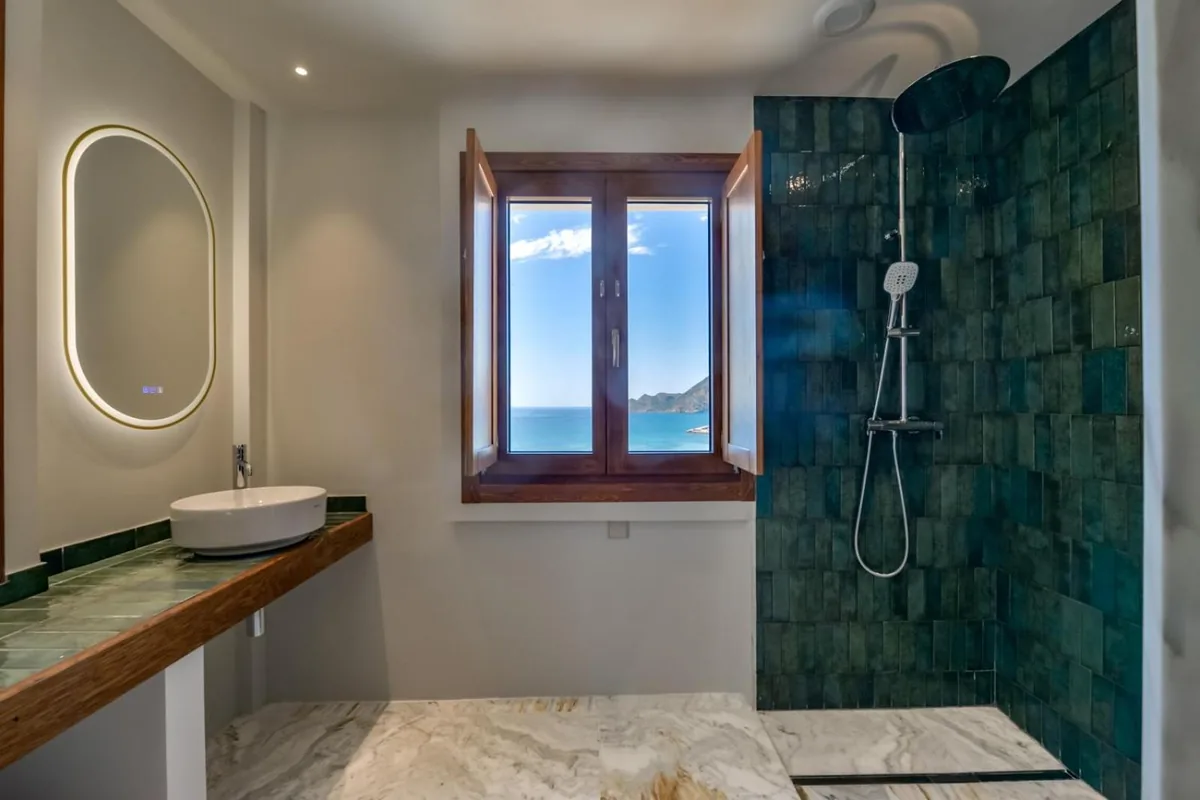 Suite bathroom with green shower tiles and a sea-view window at Las Torres