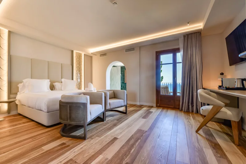 Suite bedroom and seating area with a sea-view balcony at Las Torres
