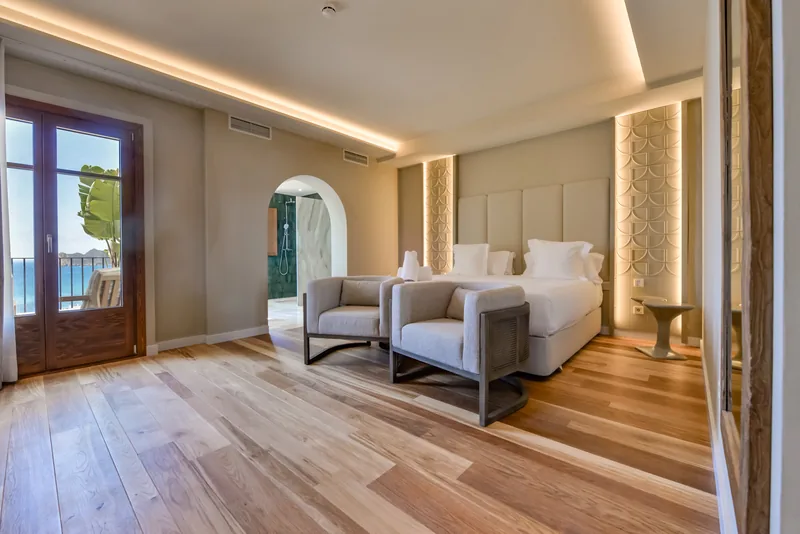 Suite bedroom with two armchairs and a balcony door at Las Torres
